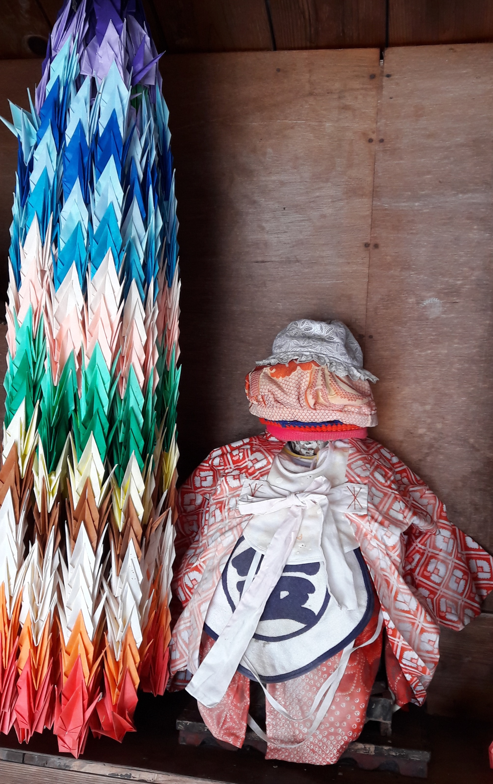 Bodhisatvos Džidzo skulptūrėlė su duodant apžadus paaukotomis prijuostėlėmis, kepurėlėmis ir kimono | M. Lebednykaitės asm. archyvo nuotr.