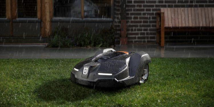 robotas vejapjovė pjauna veją prie namo kiemo