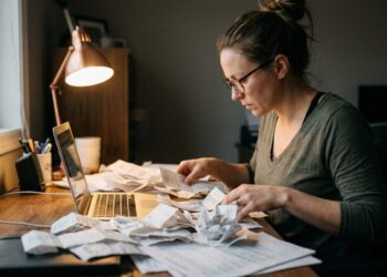 Moteris prie stalo skaičiuoja čekius