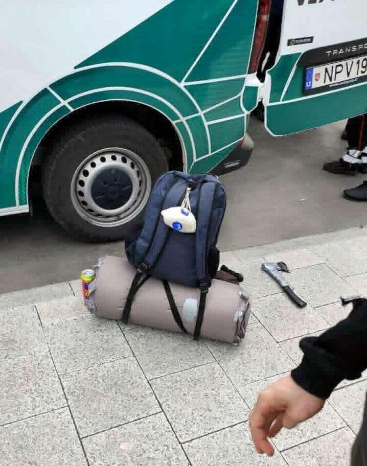 Policijos automobilis šalia kurio ant grindinio guli užpuoliko kirvis. Užpuoliką su kirviu policija sulaikė ir išvežė 