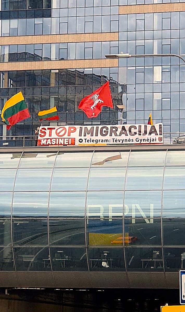 Plakatas „Stop masinei imigracijai“ virš Geležinio Vilko gatvės tunelio