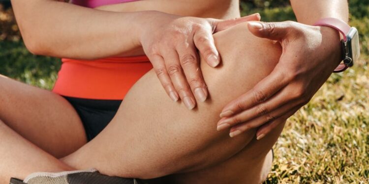 Asmuo laiko skaudantį kelį – iliustracija apie sąnarių traumas ir artroskopinių implantų naudojimą gydyme.