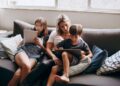 Mama su vaikais sėdi ant sofos ir naudojasi 5g namų internetu