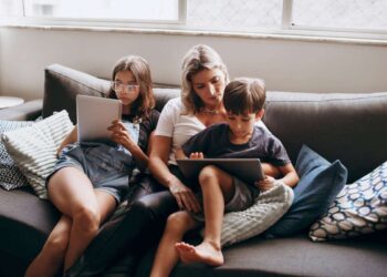 Mama su vaikais sėdi ant sofos ir naudojasi 5g namų internetu