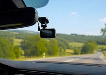 Vaizdas iš automobilio salono su prie priekinio stiklo pritvirtintu vaizdo registratoriumi.