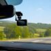 Vaizdas iš automobilio salono su prie priekinio stiklo pritvirtintu vaizdo registratoriumi.