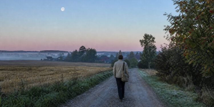 Žmogus ankstyvą rugsėjo rytą eina Lietuvos kaimo keliu, danguje matyti dylantis Mėnulis