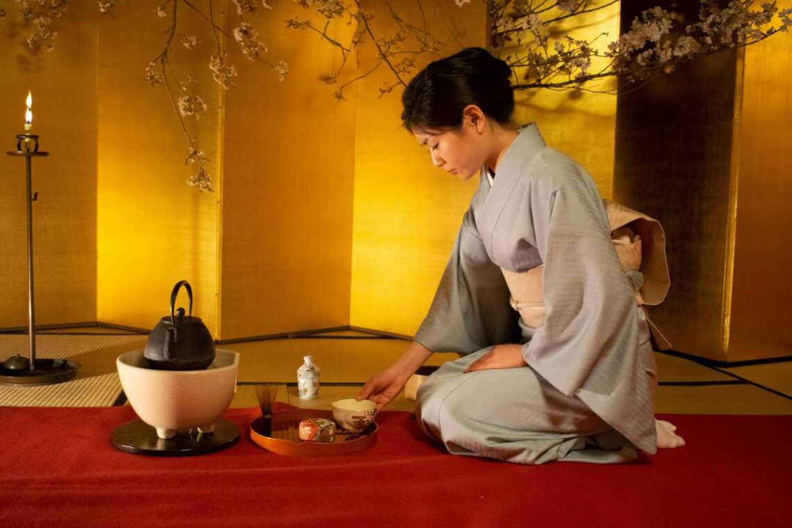 Tradicinį kimono vilkinti japonė ruošia arbatą japoniškame kambaryje