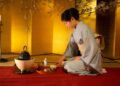 Tradicinį kimono vilkinti japonė ruošia arbatą japoniškame kambaryje