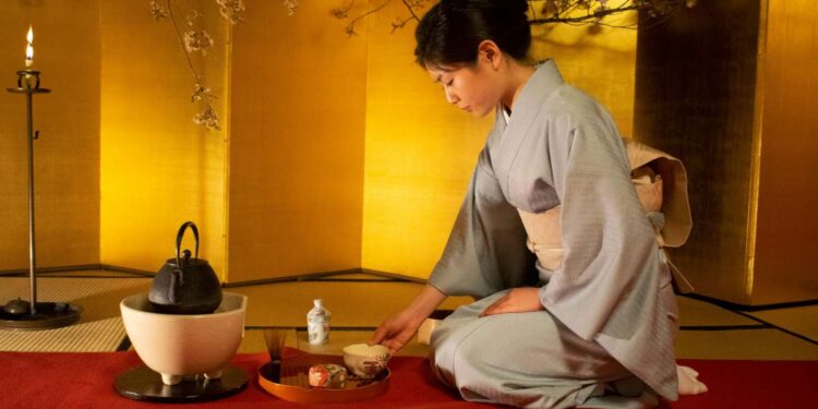 Tradicinį kimono vilkinti japonė ruošia arbatą japoniškame kambaryje