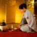 Tradicinį kimono vilkinti japonė ruošia arbatą japoniškame kambaryje