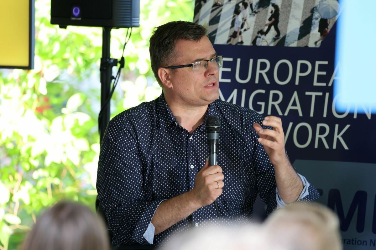 Diskusijos dalyvis kalba prie Europos migracijos tinklo stendo