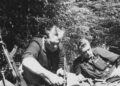 Du Lietuvos partizanai miške atokvėpio metu skaito knygą