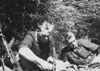 Du Lietuvos partizanai miške atokvėpio metu skaito knygą