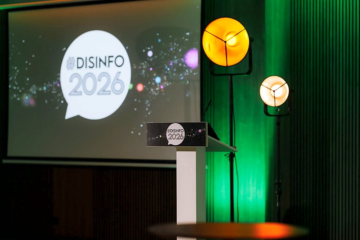 Konferencijos „#Disinfo2026“ scena, tribūna ir renginio ženklas ekrane.