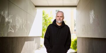Kino režisierius Audrius Stonys stovi po betonine pastato arka.