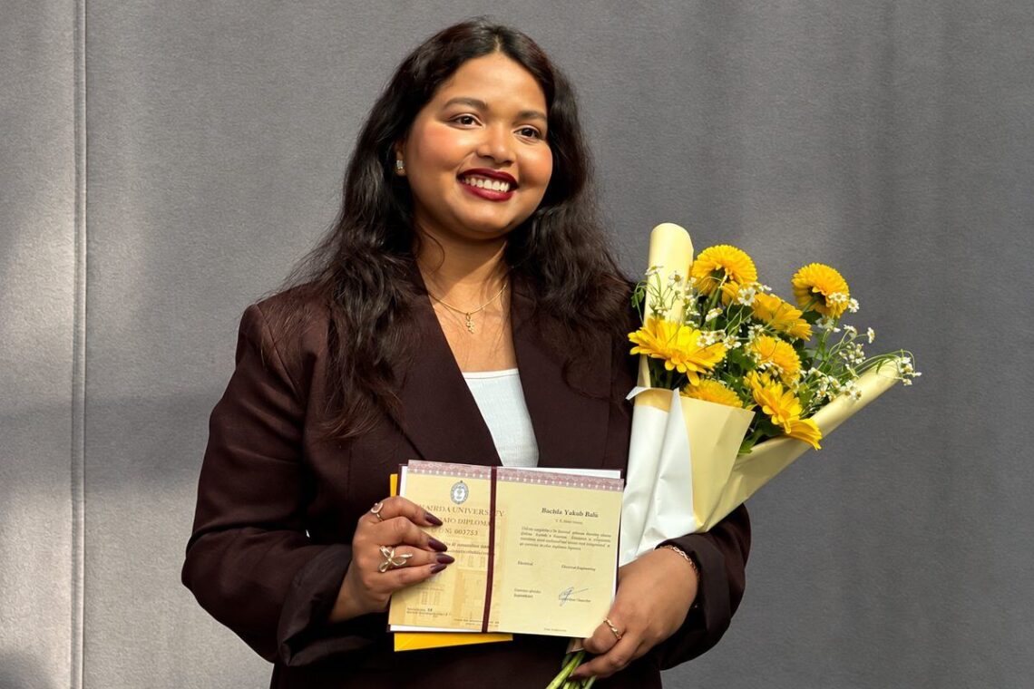 Astrofizikė Barkha Yakub Bale su daktaro diplomu ir geltonų gėlių puokšte