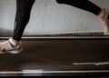 Sportinius batelius avinčio žmogaus kojos ant judančio bėgimo takelio