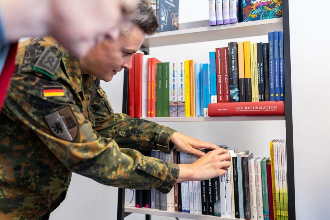 Vokietijos brigados karys dėlioja lietuvių autorių knygas lentynoje.