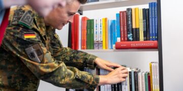 Vokietijos brigados karys dėlioja lietuvių autorių knygas lentynoje.