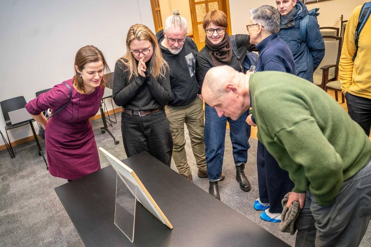 Muziejaus lankytojai susibūrę apžiūri eksponatą