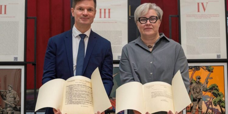P. Saudargas ir muziejaus atstovė laiko Lietuvos Vietinės rinktinės dokumentus