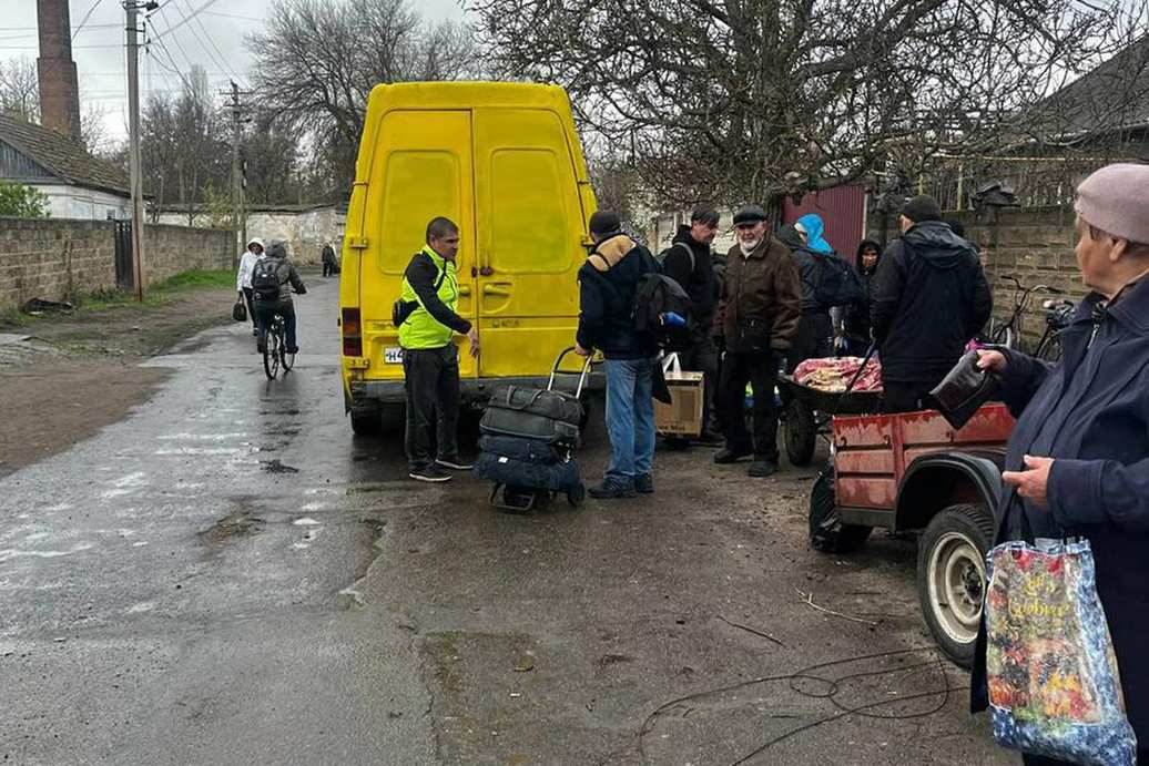 Oleškų gyventojų evakuacija prie geltono mikroautobuso.