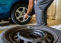 Autoservise keičiamos automobilio padangos, priekyje padėtas nuimtas ratas
