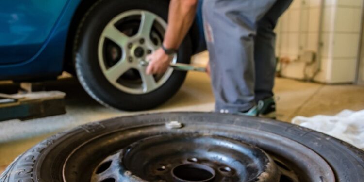 Autoservise keičiamos automobilio padangos, priekyje padėtas nuimtas ratas