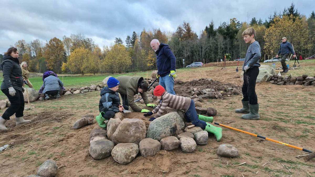 Suaugusieji ir vaikai iš lauko akmenų drauge įrengia aukurą Romuvos pilkapyne