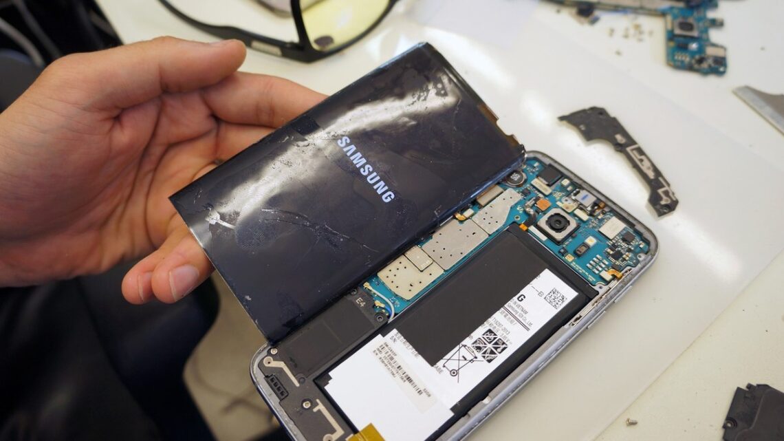 Meistras ardo išmanųjį telefoną ir tikrina jo vidines dalis