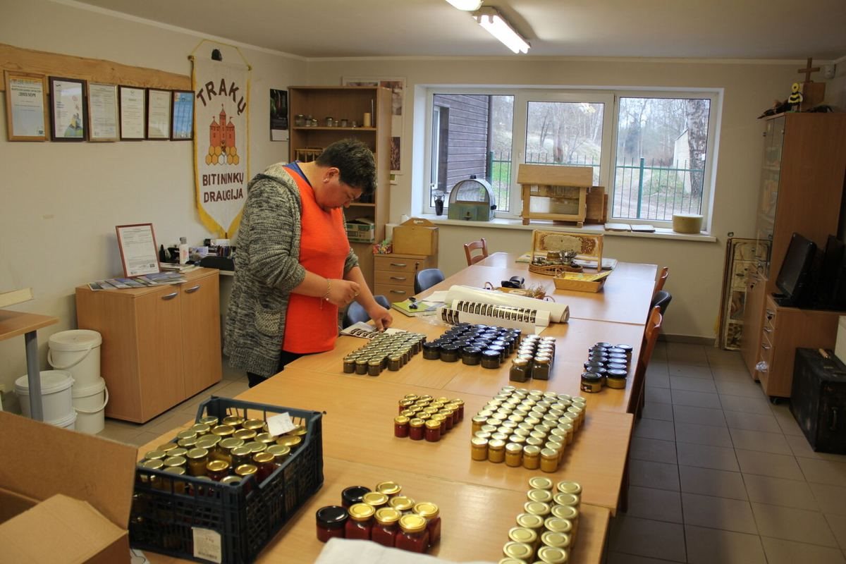 Trakų neįgaliųjų užimtumo centro dirbtuvėse žmogus ruošia parduoti medaus stiklainius